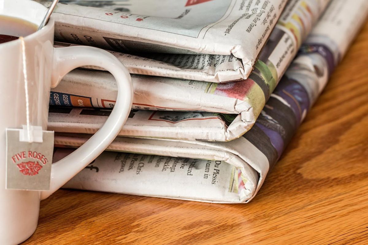 stack of newspapers next to a cup of tea on table